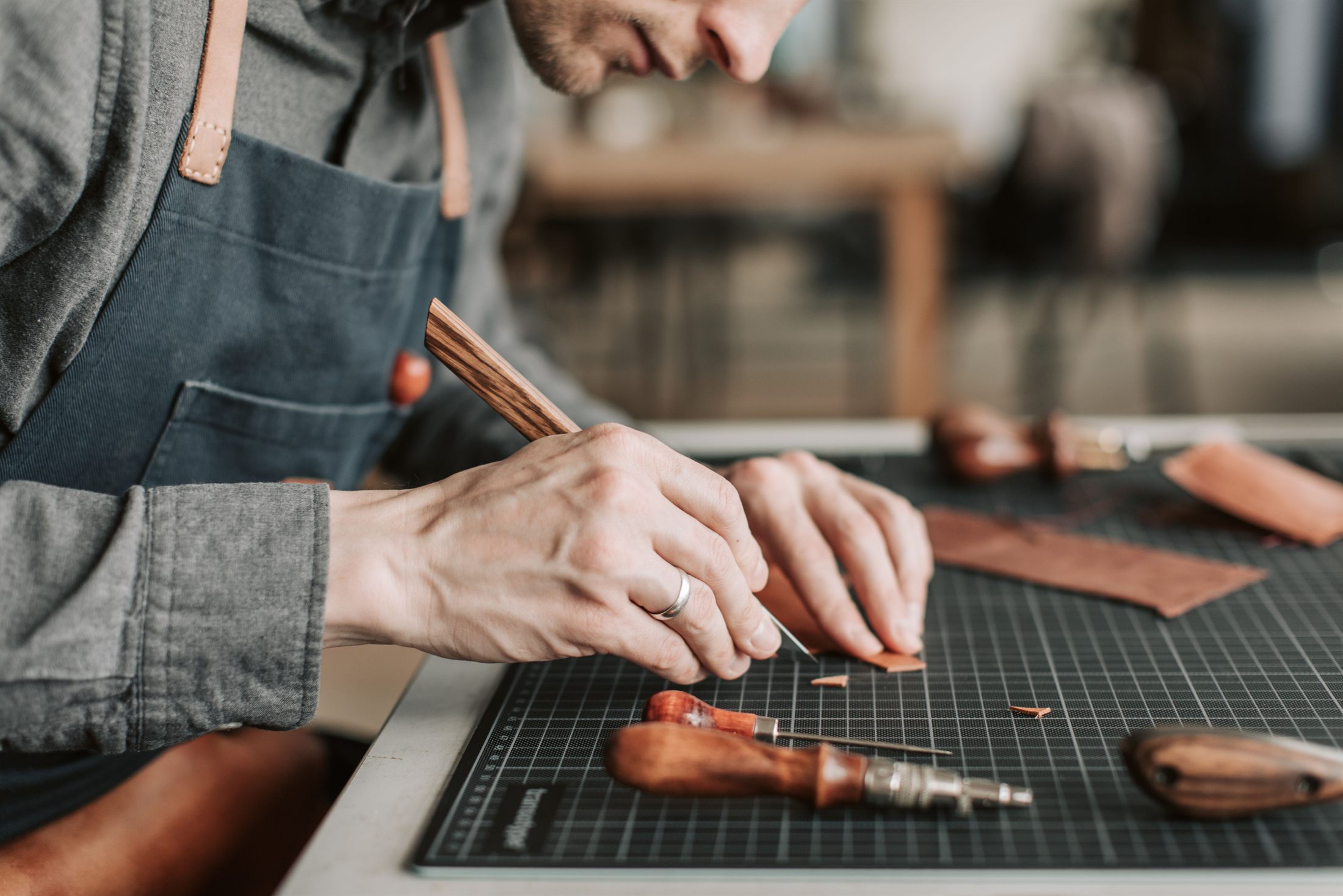 Artisan hand-cutting leather at the workbench
